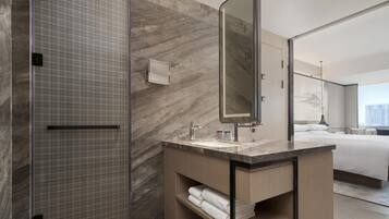 Un baño moderno con pared de mármol, un espejo grande y cabina de ducha.