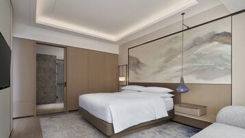 A modern hotel room with a large bed, a bedside table, a mounted artwork, and a shower area.