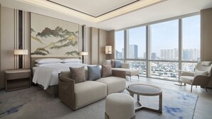 A modern hotel room with a large bed, a sofa, a round coffee table, and a view of the cityscape through large windows. - Four Points by Sheraton Suzhou, Wuzhong (Suzhou)