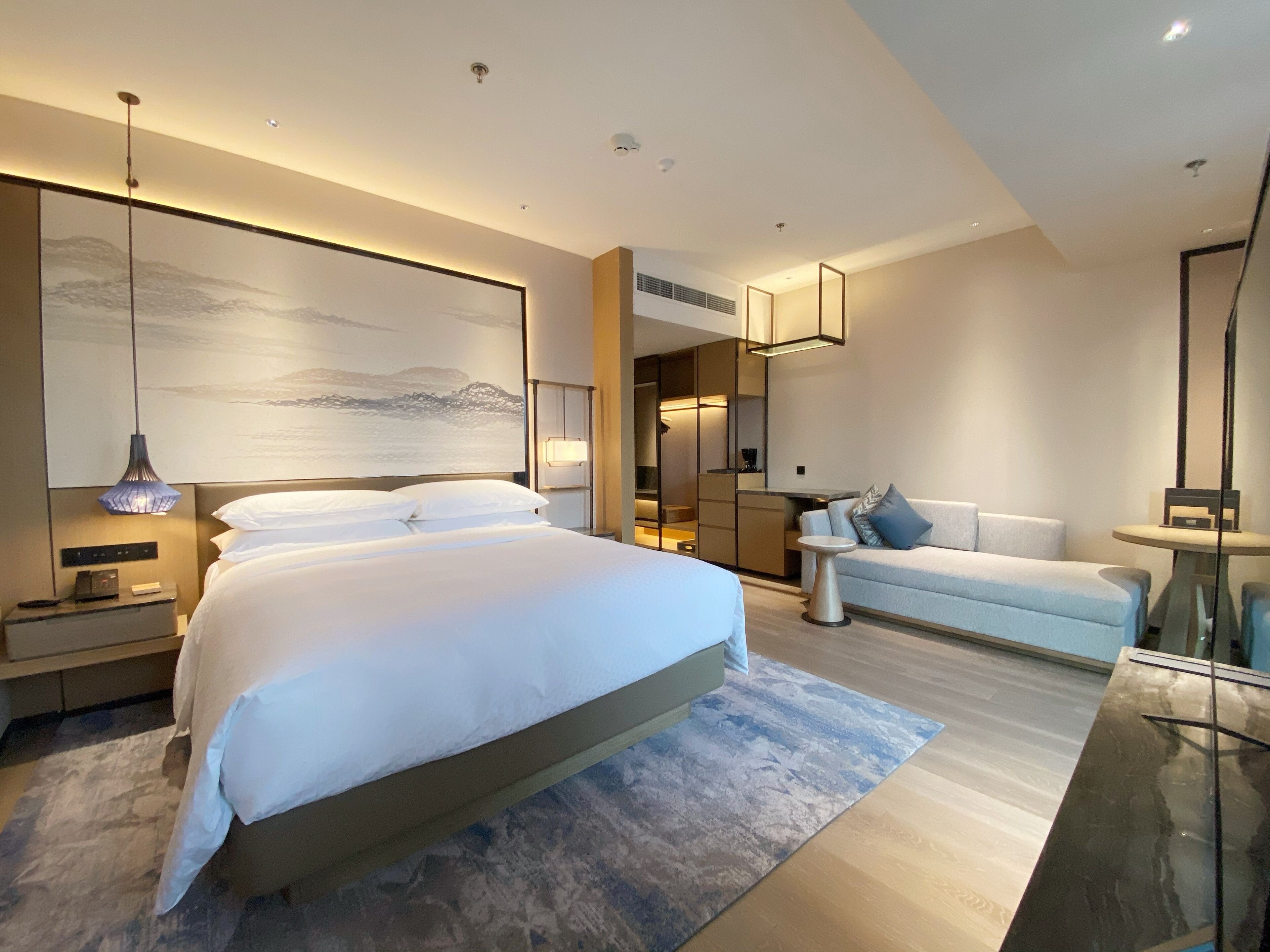 A modern bedroom with a large bed, a sofa, and a glass coffee table.