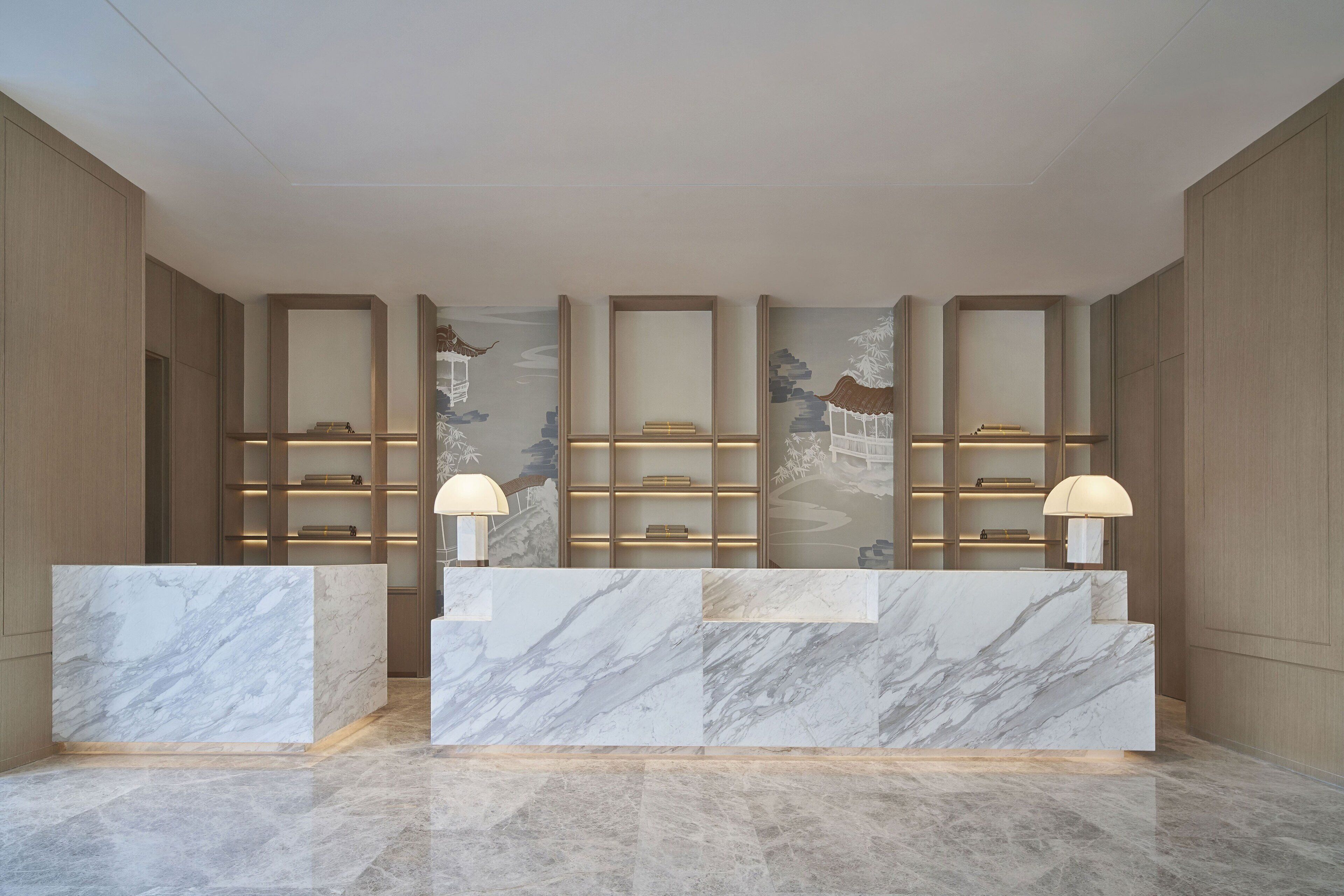 A reception area with marble counters, wall-mounted shelves, and wall-mounted lamps.