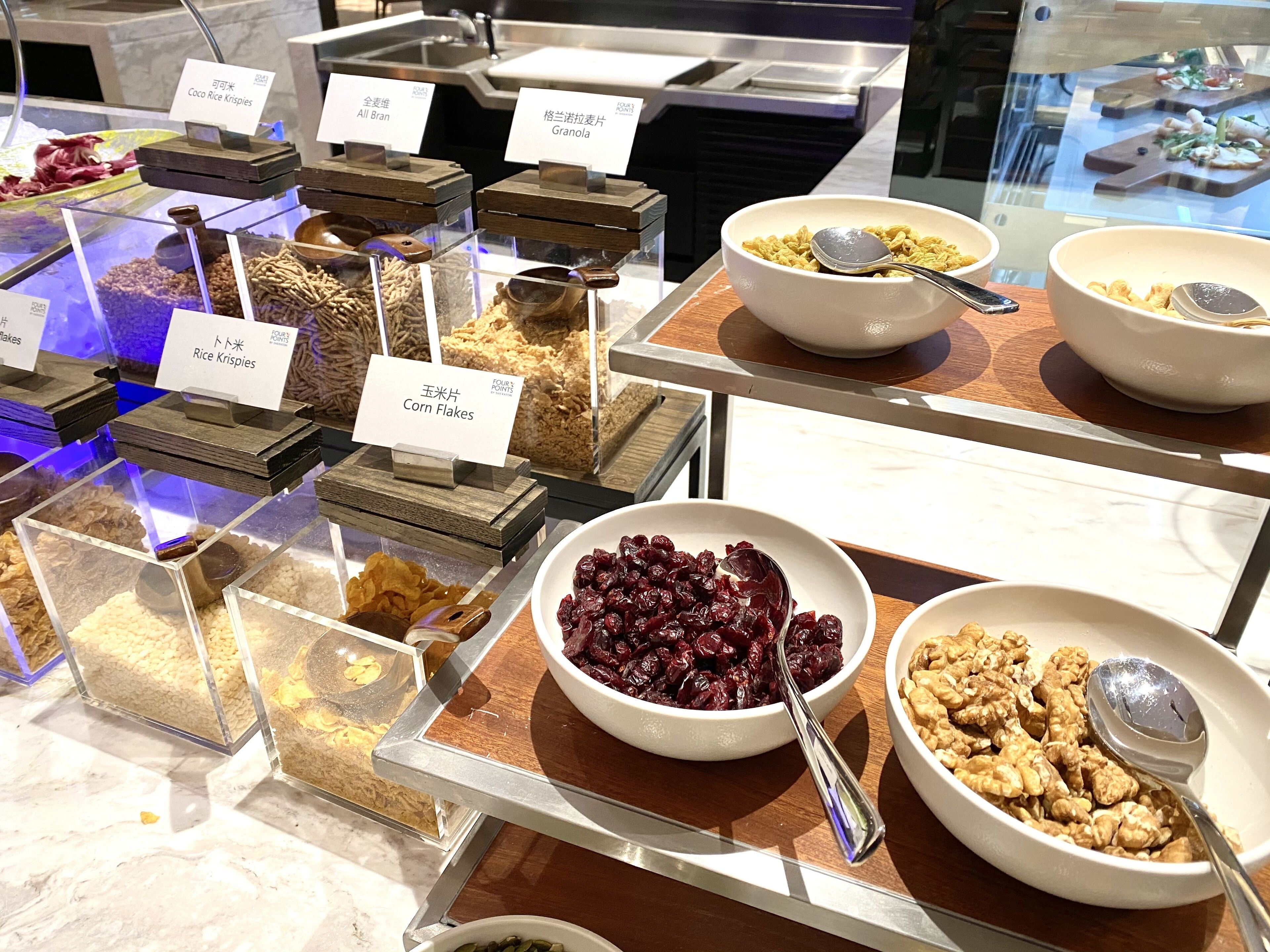 Un bufé con diversas opciones de comida, incluyendo arroz, copos de maíz, granola y nueces.