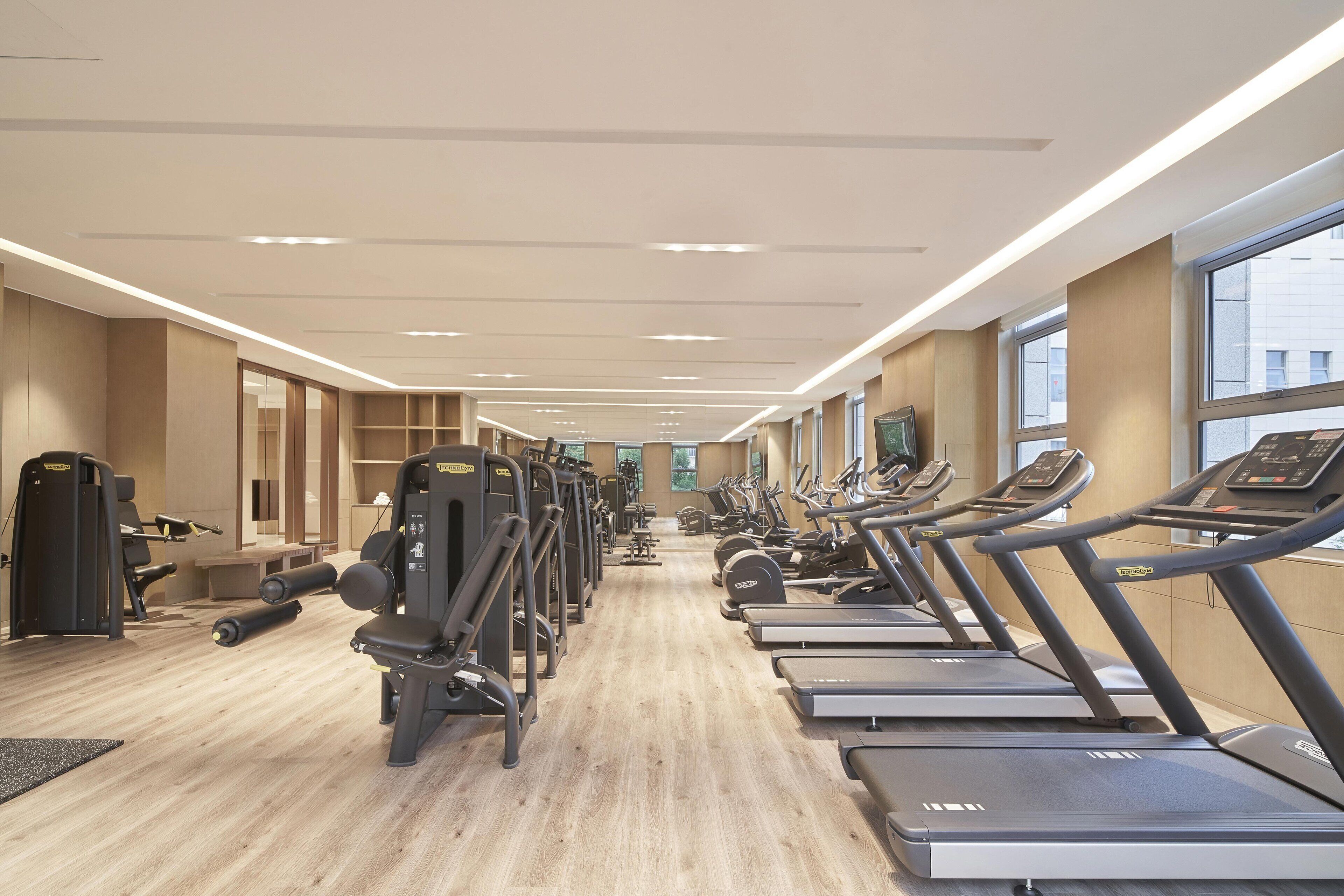 Ein Fitnessstudio mit Laufbändern, Crosstrainern und Gewichten.