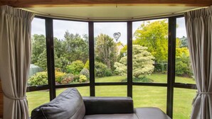 A room with a large bay window overlooking a garden. - Duvauchelle Dream (Duvauchelle)