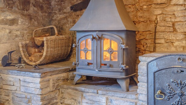 A stone fireplace with a metal stove, a wicker basket, and a metal cabinet. - 3 bedroom accommodation in Llanafan Fawr, near Builth Wells (Llanafan Fawr, near Builth Wells)