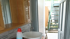 Un baño con tocador de madera, un lavabo grande blanco y un espejo encima.