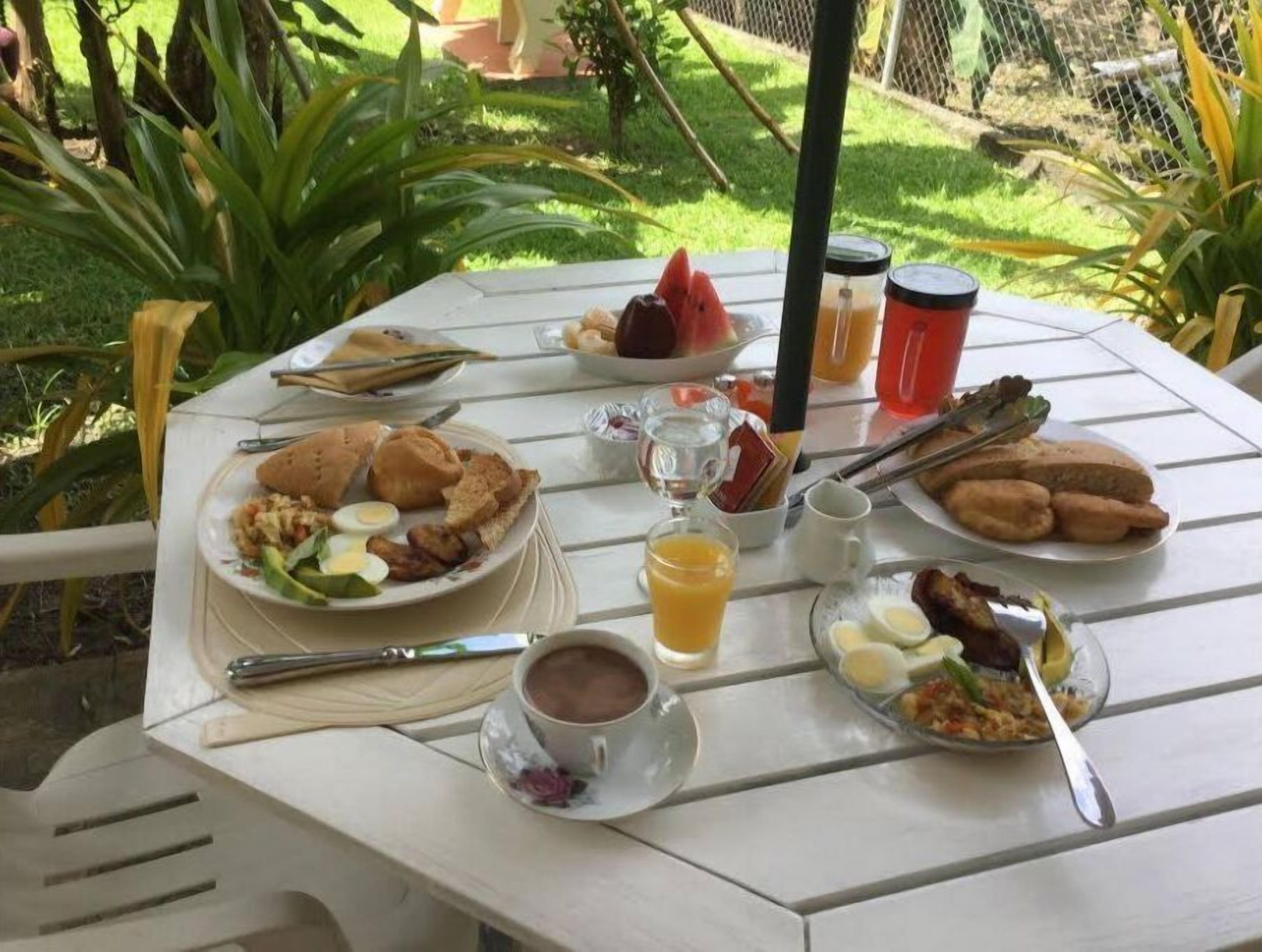 Ein Tisch im Freien mit Frühstücksangeboten, darunter Eier, Toast und Obst.