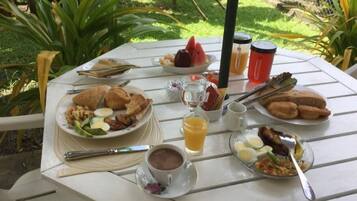 Ein Tisch im Freien mit Frühstücksangeboten, darunter Eier, Toast und Obst.