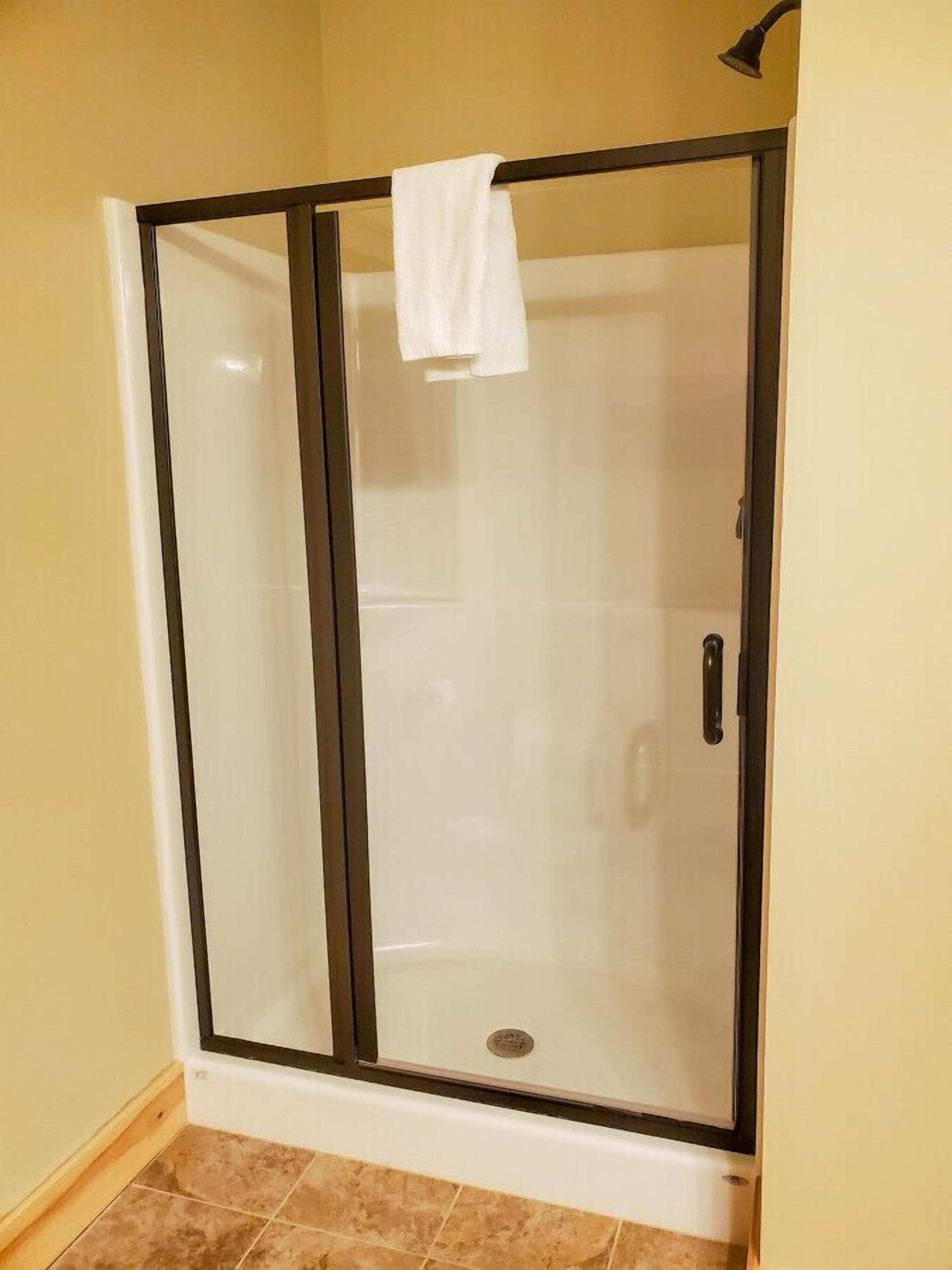 A glass-enclosed shower with a white towel hanging on the door handle.