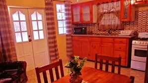 Une cuisine chaleureuse avec des meubles de rangement en bois, une table à manger avec des chaises et un four à micro-ondes.