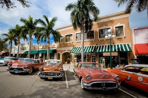A street lined with vintage cars parked in front of a building with a green awning and palm trees. - Richard's Hotel (Hollywood)