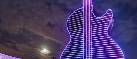 Un edificio grande con forma de guitarra, iluminado con luces moradas y azules.