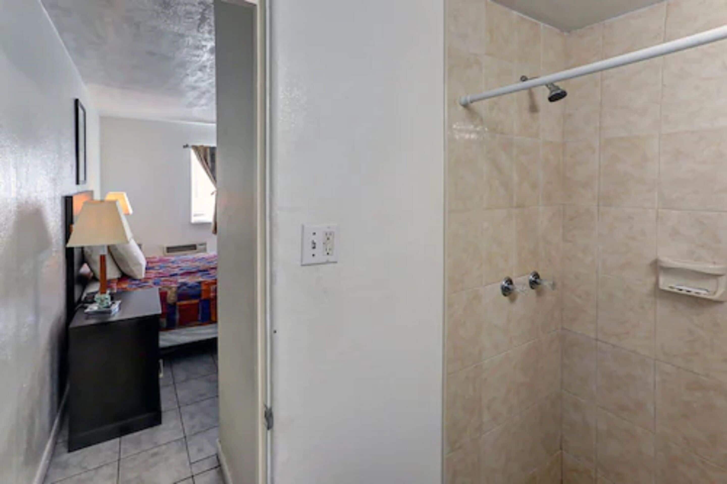 A bathroom with a shower, a towel rack, and a small sink.
