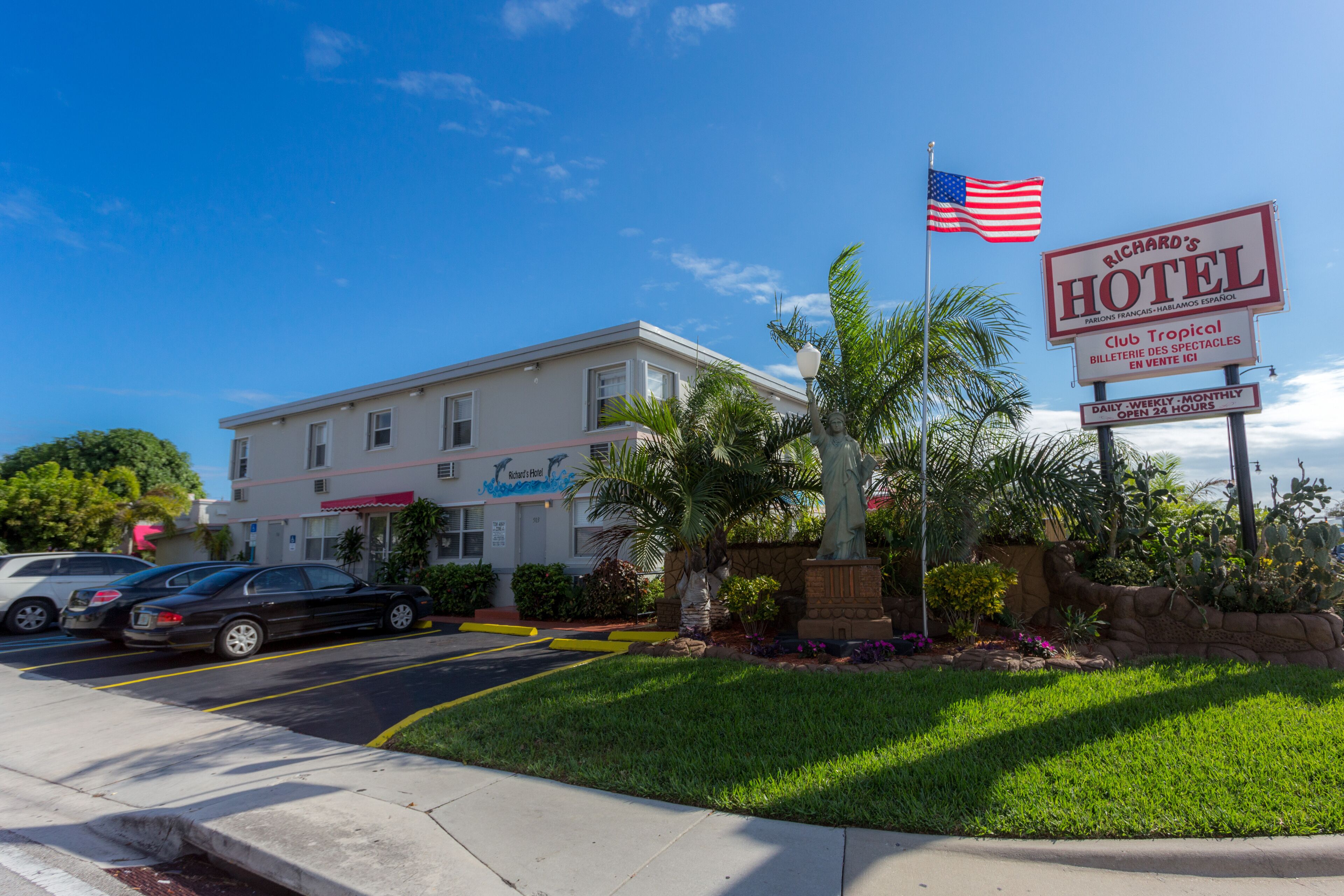 Um hotel com placa, bandeira e gramado bem cuidado.