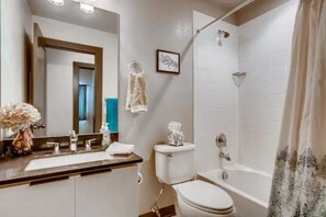 Un baño moderno con un espejo grande, un inodoro, una bañera y una ducha.