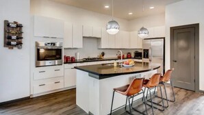 A modern kitchen with white cabinetry, stainless steel appliances, and a central island with bar stools. - 4 bed, 4 bath, Minutes to Downtown Denver (Denver)