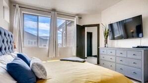 A bedroom with a bed, a TV, a dresser, and a window with curtains. - 4 bed, 4 bath, Minutes to Downtown Denver (Denver)