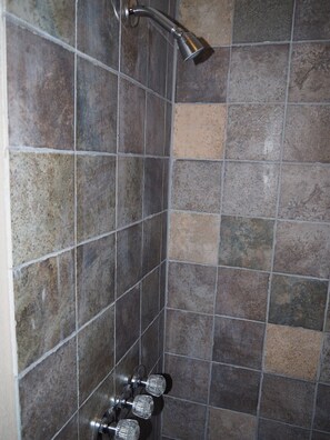 Enjoy a refreshing shower experience with a vertical showerhead mounted on a tiled wall.