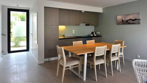 A modern kitchen with a dining area, featuring a wooden table and chairs, a built-in oven, and a view of the outdoors. - Villa for 6 people 300m from the beaches for 6 people (La Palmyre)