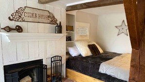 Una habitación acogedora con chimenea, una cama y un letrero que dice 'CIDER HOUSE'.
