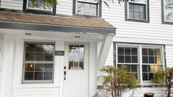 A white house with a front door, two windows, and a small porch area.