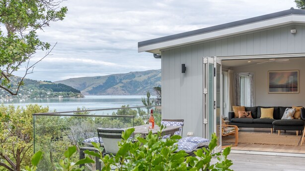 Ein modernes Haus mit einer Terrasse mit Blick auf einen See, einem Sofa und einem Essbereich.