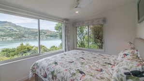 Ein Schlafzimmer mit einem großen Fenster und Blick auf einen See und Hügel.