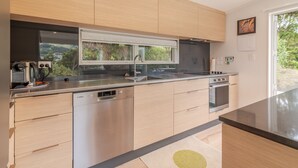 Eine moderne Küche mit integrierten Geräten, einem großen Fenster und Blick ins Grüne.