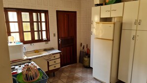 A compact kitchen with a sink, a refrigerator, and cabinets. - 800 mts da Praia (SP)
