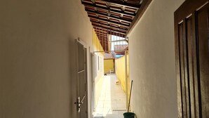 A narrow hallway with a tiled floor, a wooden ceiling, and a door on the left. - 800 mts da Praia (SP)