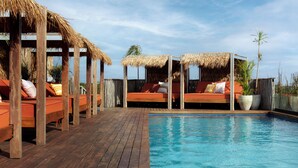 A wooden deck with a pool, thatched-roof seating areas, and potted plants. - Aluna Resort Tulum (Tulum)