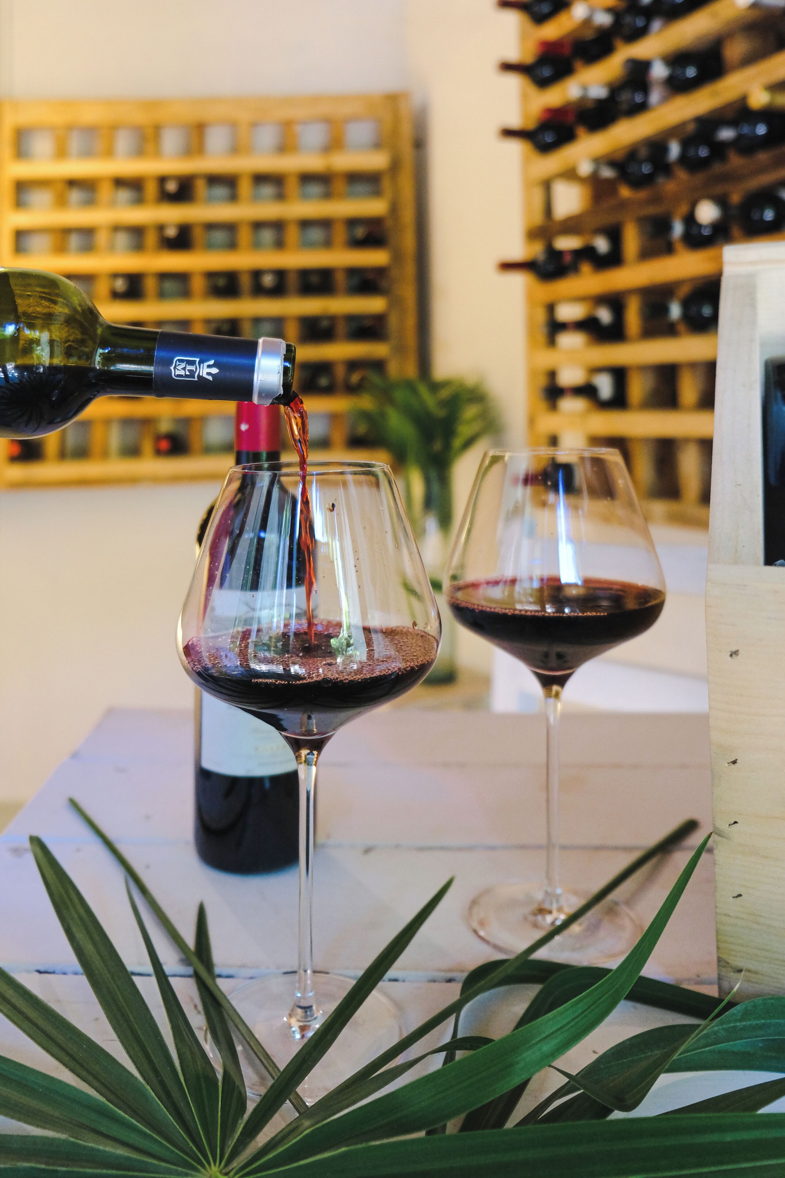 Deux verres à vin sont posés sur une table, et du vin est versé d’une bouteille dans l’un d’eux.