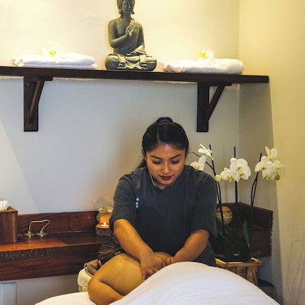 A room with a bed, a statue, and a shelf with towels.