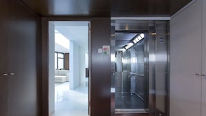 An elevator interior with a metallic finish, a glass door, and a control panel. - Atlantic House (Ponta Delgada)
