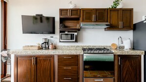 Uma cozinha com armários de madeira, fogão a gás, micro-ondas e televisão de tela plana.
