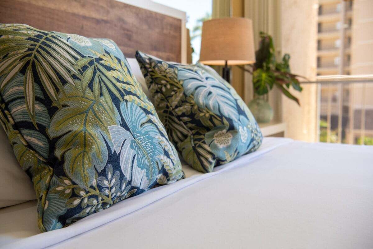 Een bed met kussens met bloemenprint en een houten hoofdbord.