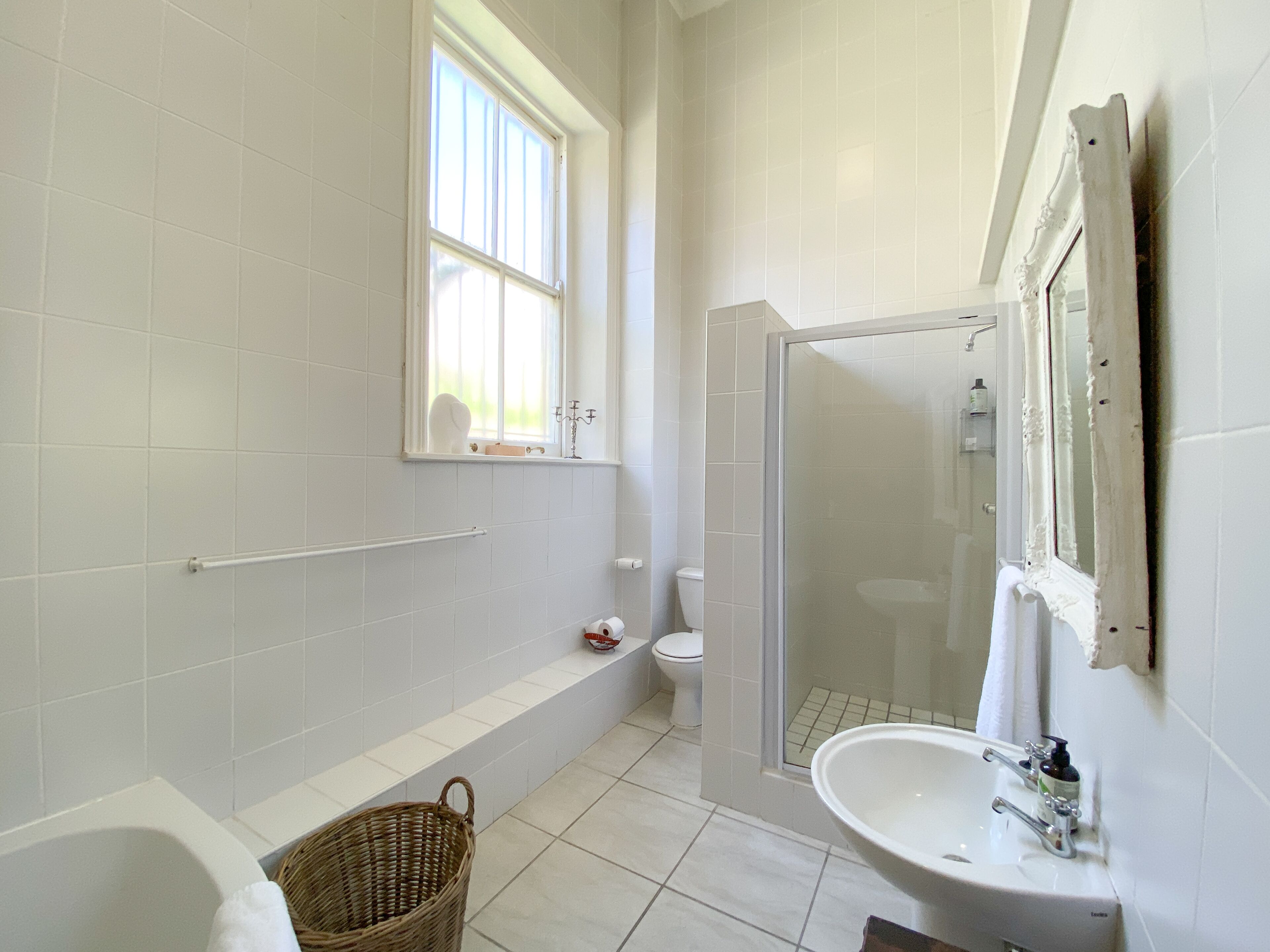 A bathroom with a bathtub, a shower, a sink, and a window.