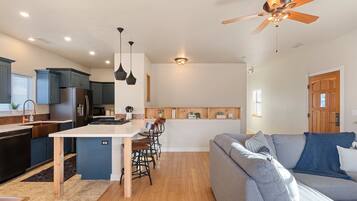 Une cuisine moderne avec des meubles de couleur bleu foncé, un îlot central blanc et un coin repas avec des chaises en bois.