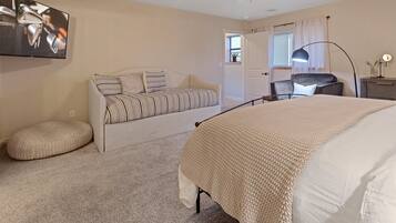 A bedroom with a bed, a sofa, a desk, and a chair.