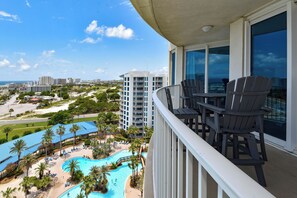 Un balcon avec vue sur une piscine, des palmiers et le paysage urbain.