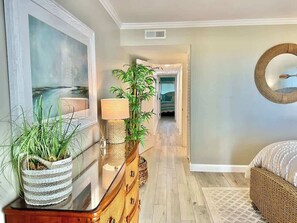 A hallway with a mirror, a lamp, a potted plant, a wicker basket, and a wicker bed.