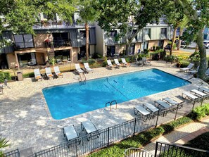 Relax by the rectangular pool surrounded by comfortable lounge chairs and sunbeds, set amidst a modern building with large windows.