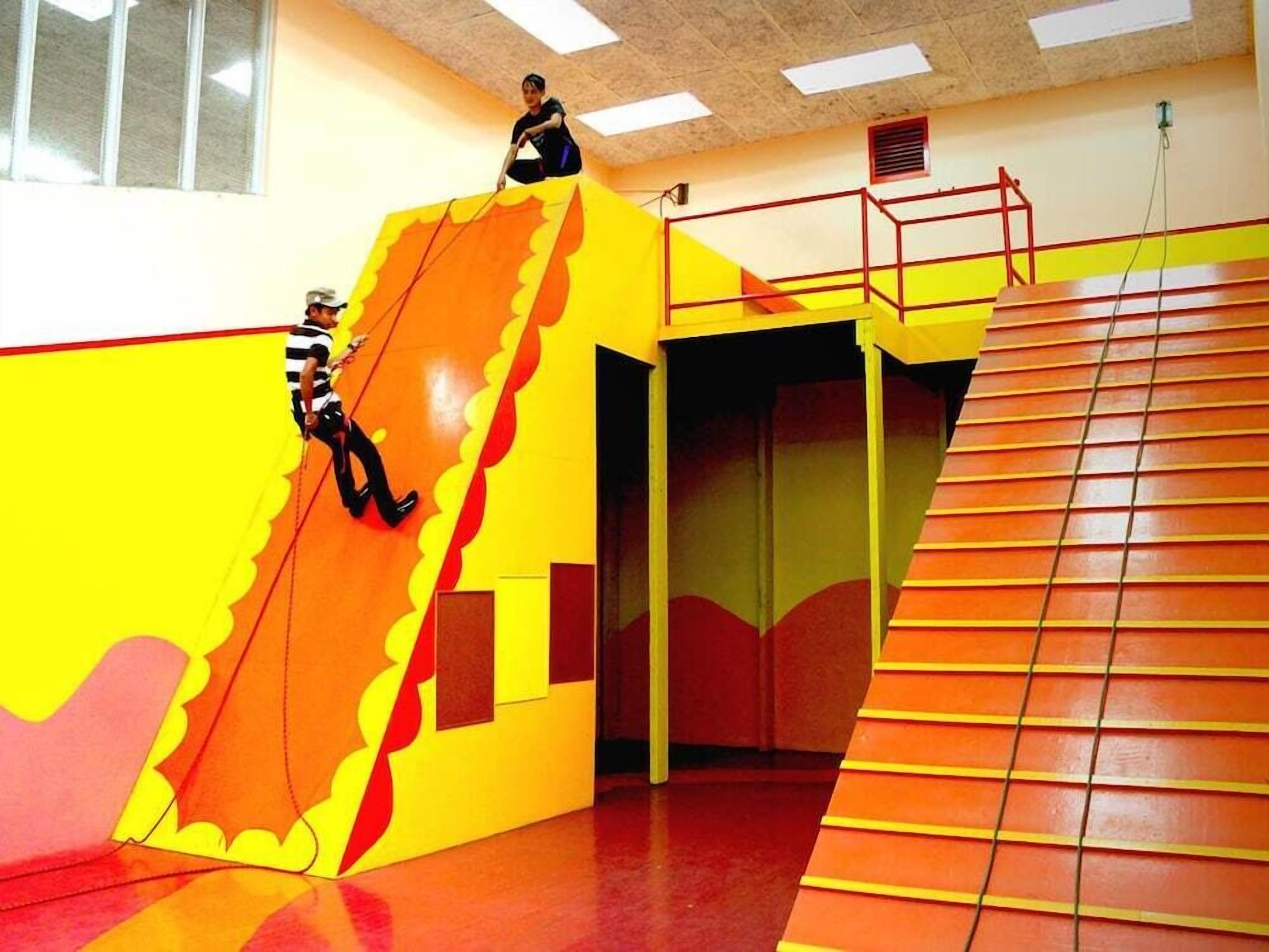 A brightly colored indoor play area with a slide and a climbing wall.