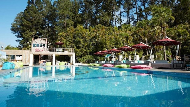 A swimming pool with a lifeguard tower, lounge chairs, and umbrellas. - Resorts World Awana (Genting Highlands)