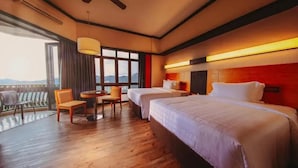 A hotel room with two beds, a dining table with chairs, a ceiling fan, and a large window offering a view of the mountains. - Resorts World Awana (Genting Highlands)