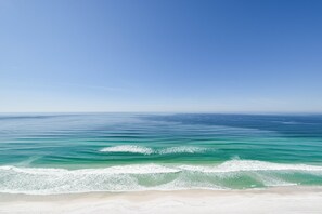 Une plage avec une eau d’un bleu limpide et un rivage sablonneux.