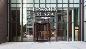 De ingang van Lincoln Plaza in Londen, met een draaideur en een glazen gevel.