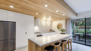 Uma cozinha moderna com uma ilha central, banquetas e vista para a área externa.