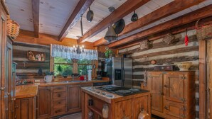 A rustic kitchen with wooden cabinets, a central island, and hanging pots.
