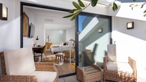 A modern hotel room with a balcony, wicker furniture, and a glass door leading to a dining area. - Stupendo-3br-suite & Terrace- Center- A/conditioning (Lisboa)